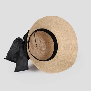 Détail d'un chapeau de soleil en raphia tressé avec nœud en mousseline et bande intérieure