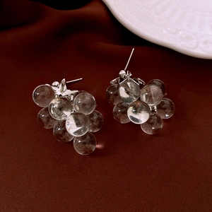 Detailed close-up of crystal grape cluster earrings with silver leaves on silk fabric