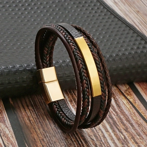Close-up of men's braided leather bracelet with golden magnetic clasp on a leather book