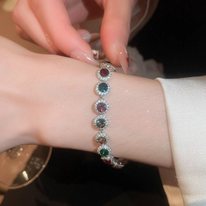 Vue détaillée d'un bracelet en argent avec zircons colorés au poignet d'une femme