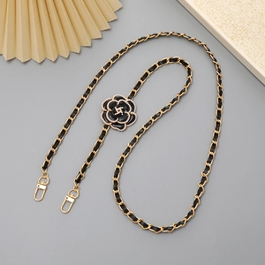 Detail of gold metal chain with black leather strap, camellia flower and pearls