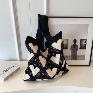 Knitted tote bag with black and white heart patterns shown in a stylish lifestyle setting