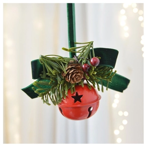 Close-up of a red metal Christmas bell with velvet bow, pine needles and pine cone