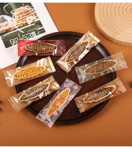 Detailed close-up of individually wrapped boat-shaped pastries on a dark wooden tray