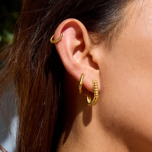 Three-piece gold stainless steel earring set featuring twisted textures and smooth oval hoops