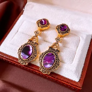 Vintage oval drop earrings with purple stones in antique gold setting in a jewelry box