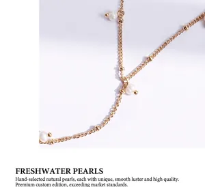Macro detail of delicate gold chain with natural freshwater pearls on a white surface