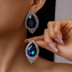 Macro view of vintage royal blue teardrop earrings with halo diamond settings