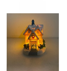 Detail view of a glowing resin Christmas house with warm LED lights and snowy texture