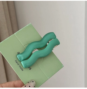 Close-up of mint green wavy duckbill hair clips on a handmade display card