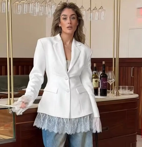 Detail view of lace trim on the sleeves and hem of a white long-sleeve blazer