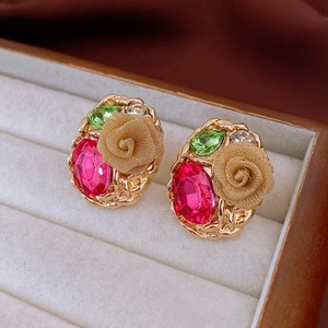 Macro view of vintage gold flower earrings with pink and green gemstones and rhinestones
