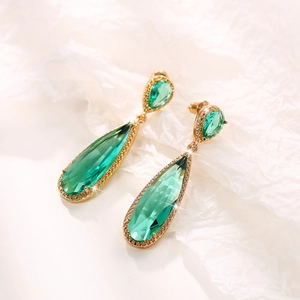 Detailed macro view of teardrop emerald zircon earrings with gold-plated trim