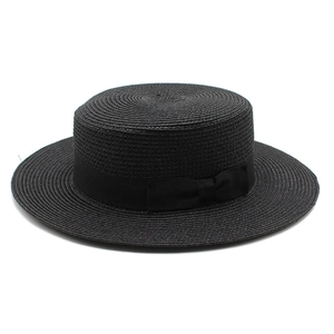 Detail of the woven texture and black ribbon bow on a black flat-top boater straw hat