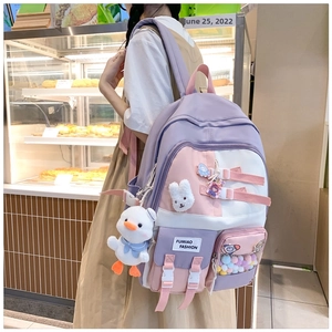 Girl wearing a purple and pink patchwork backpack with a cute duck plush and front pocket
