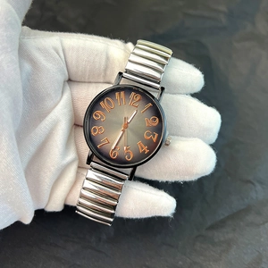 Detail of vintage watch with orange large numerals and silver elastic stainless steel band