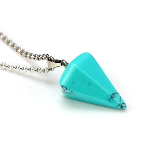 Detail of bohemian turquoise triangle pendant necklace with silver chain on white background