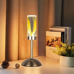 Close-up of a warm LED night light with a glowing wheat pattern inside a bronze base