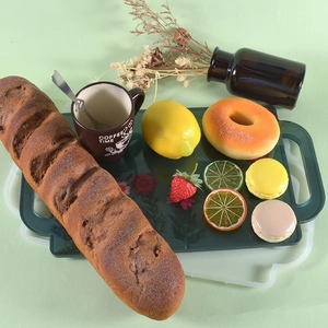 Macro detail of artificial bread and fruit set on a rectangular tray for home decoration