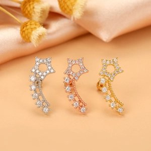 Detailed macro view of star-shaped zircon cartilage earrings in gold, silver, and rose gold