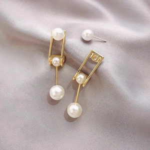 Detail of C-shaped pearl earrings with gold frame on elegant grey silk fabric
