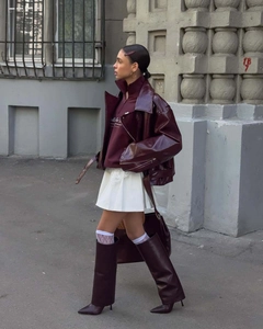 Detail of dark burgundy patent leather moto jacket with stylish white lace pleated skirt