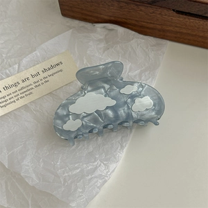 Detail of blue translucent resin hair claw clip with 3D white cloud patterns