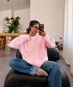 Detail of pink V-neck knit sweater featuring relaxed shoulder design and soft texture