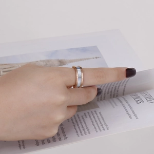 Close-up of rose gold Roman numeral ring with shell inlay worn on a female hand