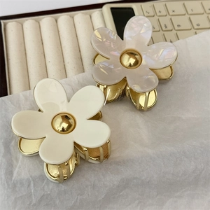 Macro detail of acetate flower hair claw clips with pearlescent finish and gold metal teeth