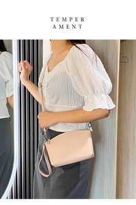 Pink crossbody bag with metal zipper and adjustable strap shown on a model