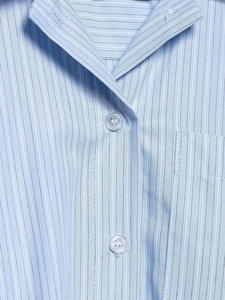 Gros plan détaillé d'une chemise à rayures bleu clair avec col et boutons en résine
