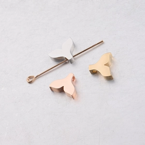 Detailed view of polished whale tail jewelry charms in silver, gold, and rose gold finishes