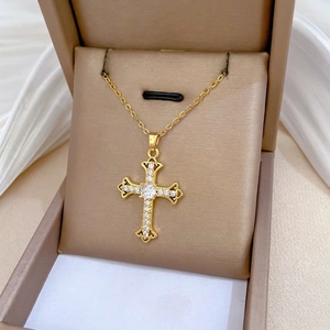 Elegant 18K gold titanium cross necklace with sparkling cubic zirconia on beige satin