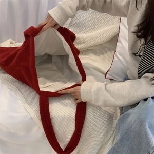 Detailed view of the red plush tote bag interior with a white lining and storage pocket