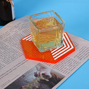 Detail of hexagon orange resin coaster with white stripes and embedded gold glitter