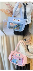 Detail of plush tote bag with clear window showing cute cartoon ears and anime character pins