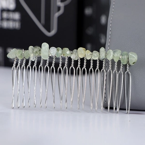 Close-up of handmade hair comb with light green raw crystals and silver wire wrapping