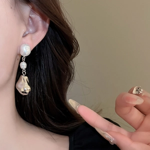Gros plan de boucles d'oreilles élégantes en perles baroques portées par un mannequin