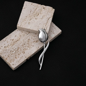 Elegant silver tulip metal brooch with a smooth finish displayed on beige stone