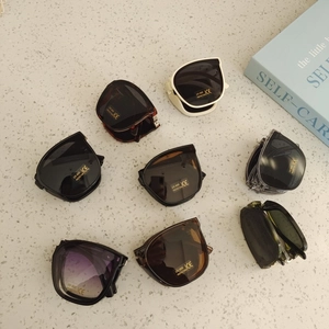 Foldable UV400 kids sunglasses in multiple colors on a textured stone background