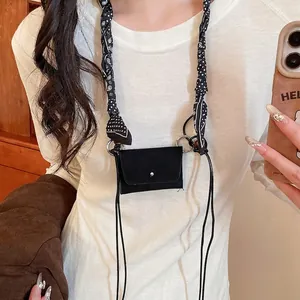 Retro black mini neck bag with bandana scarf strap and silver button closure on a warm background