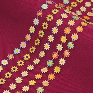 Macro shot of colorful enamel daisy charms on stainless steel chains over red knit