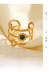 Macro shot of gold sun and star ring with green gemstone on beige satin fabric