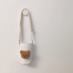 Detail of white quilted cotton bottle holder with cute brown teddy bear embroidery