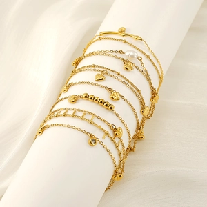 Close-up of dual-layer 18K gold-plated anklets with heart charms and pearls on white silk