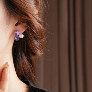 Detail of luxury earrings with white pearl and purple faceted crystals on gold base