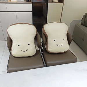 Close-up of two soft cartoon toast bread plush pillows with cute smiling faces on a chair