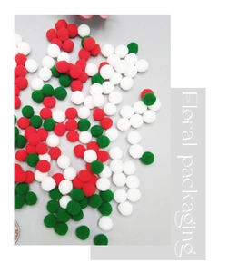 Close-up of red, white, and green Christmas pom poms with a coin for scale reference