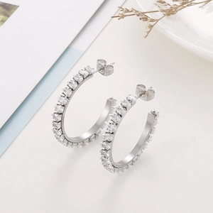 Detail of C-shaped silver earrings with marquise-cut white zircons on a white background